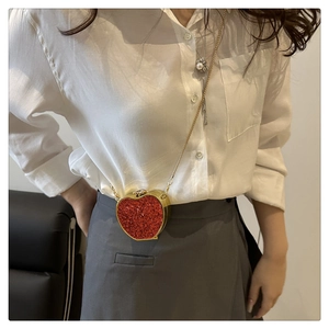Detail of red glitter heart-shaped mini bag with a sleek gold chain strap and metal frame