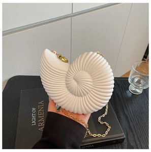 Detail of white shell-shaped handbag featuring radial texture and a gold chain strap