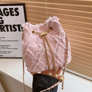 Pink frayed denim bucket bag with gold chain strap and pearl drawstring accents