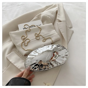Close-up of a silver egg-shaped acrylic clutch bag with a rippled metallic surface and chain