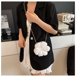 Close-up of white flower clutch bag with gold chain strap worn as a crossbody purse