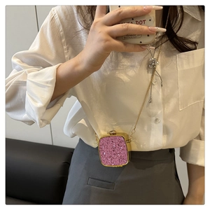 Pink glitter mini acrylic box bag with golden chain strap shown on a white shirt
