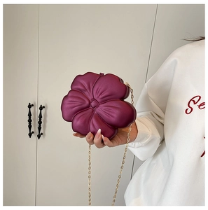 Close-up of burgundy flower-shaped evening bag with petal texture and gold chain strap