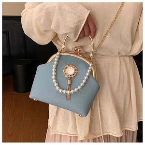 Detail of light blue shell bag with vintage gold kiss lock and pearl fringe tassel charm