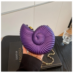 Detail of purple acrylic shell clutch with spiral texture and golden chain strap