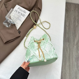 Close-up of denim bucket bag with quilted rhomboid pattern and pearl drawstring detail