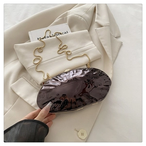 Detail view of dark brown glossy shell bag with wave texture and gold chain strap