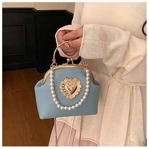 Close-up of light blue leather shell bag with pearl heart buckle and metal handle