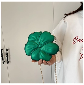 Detail of green acrylic flower shaped mini bag with metallic finish and gold chain strap