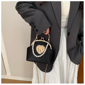 Detail of vintage black leather bag featuring pearl handle and golden heart emblem