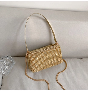 Close-up of golden rhinestone pillow bag with leather handle and metal chain strap