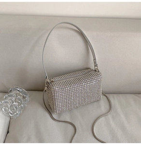 Detail of silver rhinestone pillow bag with metal chain strap on minimalist background