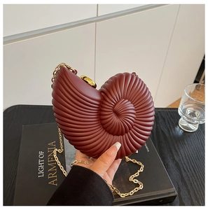 Macro detail of burgundy snail-shaped acrylic shell bag with spiral relief texture