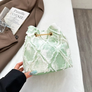Detail of green denim bucket bag with distressed edges and elegant gold chain drawstring