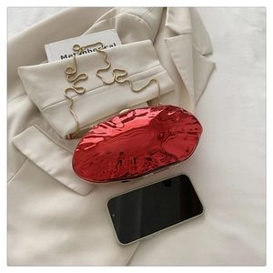 Detail view of red glossy oval clutch with metallic ripple texture and gold chain strap