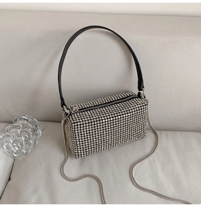 Detailed view of silver rhinestone crossbody bag with black handle and metal chain strap