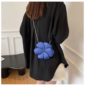 Detailed view of blue flower-shaped acrylic clutch bag with delicate gold chain strap