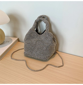 Detail of silver rhinestone bucket bag with shiny metallic chain on wood surface