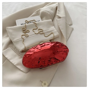 Macro detail of glossy red shell evening bag featuring a premium gold snake chain strap