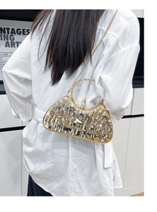Detail of gold liquid metal evening bag with round handle on white shirt