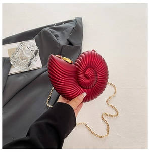 Macro shot of dark red nautilus acrylic shell bag with pearlescent finish and gold chain