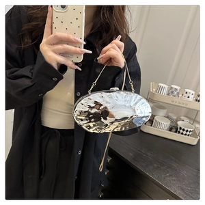 Detail of silver metallic evening clutch with wave texture and thin gold chain strap