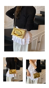 Close-up of golden rectangular acrylic clutch with C-shaped buckle and metal chain strap