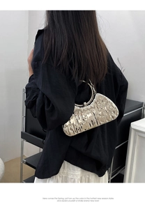 Détail d'un sac à main argenté avec texture lave irrégulière et poignée ronde