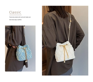 Detail view of denim bucket bag with frayed quilted texture and pearl drawstring accents