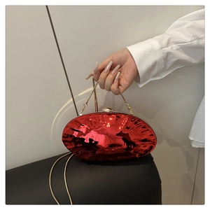 Macro detail of red shell-shaped evening clutch with pleated texture and gold chain