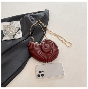 Macro detail of wine red conch-shaped acrylic handbag with gold metal chain
