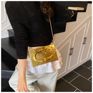 Close-up of a gold acrylic box bag with a large metal buckle and elegant chain strap