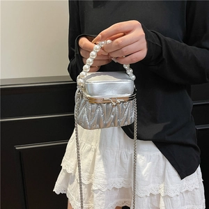 Silver quilted mini bag with pearl handle and chain strap shown on model's shoulder