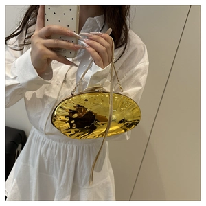 Detail of gold oval evening bag with rippled metal texture and fine chain strap
