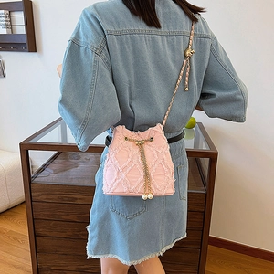 Detail of pink denim bucket bag with quilted fraying and pearl drawstring charm