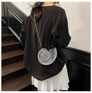 Chic shell-shaped acrylic crossbody bag with silver chain strap worn by a model