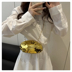 Macro detail of gold irregular shell clutch bag with liquid ripple texture and chain