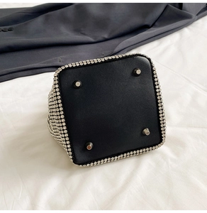 Detail view of rhinestone bucket bag base with protective silver metal feet and black leather