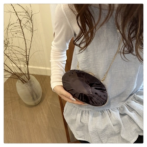 Chic purple oval acrylic clutch bag with wave texture and gold chain on model