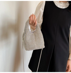 Close-up of sparkling silver rhinestone bucket bag with metal chain strap on model