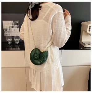 Detail of dark green conch shell bag with spiral texture and gold chain strap