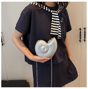 Detail of silver conch shell clutch with metallic texture and sleek chain strap