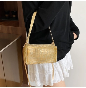 Detailed view of women's gold rhinestone shoulder bag with elegant metallic strap and crystals