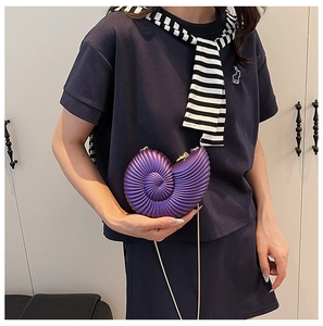 Detail of purple acrylic nautilus shell clutch with golden chain strap on a model