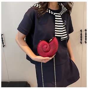 Detail of red acrylic nautilus shell clutch with luxury gold chain and metallic finish