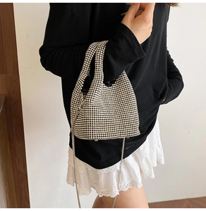 Close-up of sparkling rhinestone bucket bag with silver chain strap worn by a model