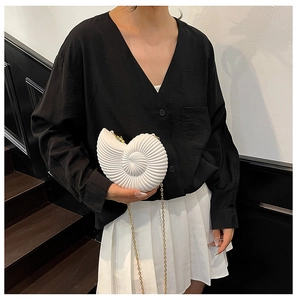 Chic pearl white shell-shaped acrylic clutch with gold chain on model in black outfit