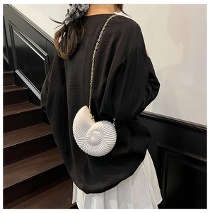 Detailed view of white acrylic shell clutch with gold chain strap on a model