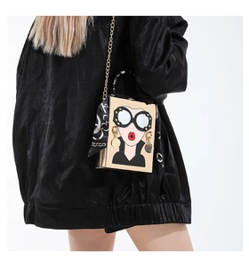 Détail du sac boîte avec visage cartoon iconique, poignée métal et foulard en soie