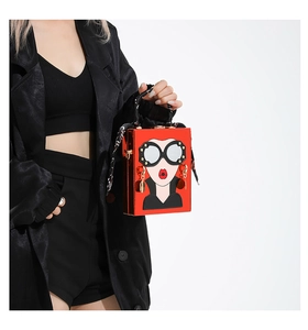 Detail of red box clutch bag with cartoon girl print and silk scarf wrapped handle